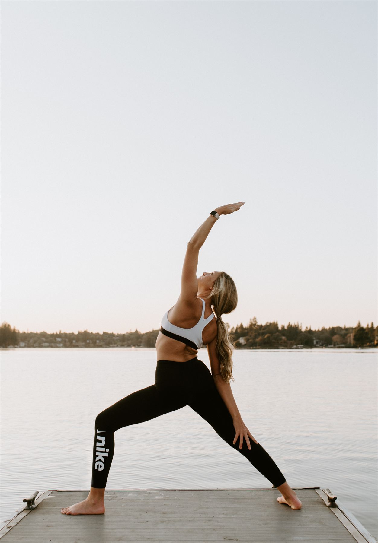 A woman in a yoga pose on a dock at sunrise
